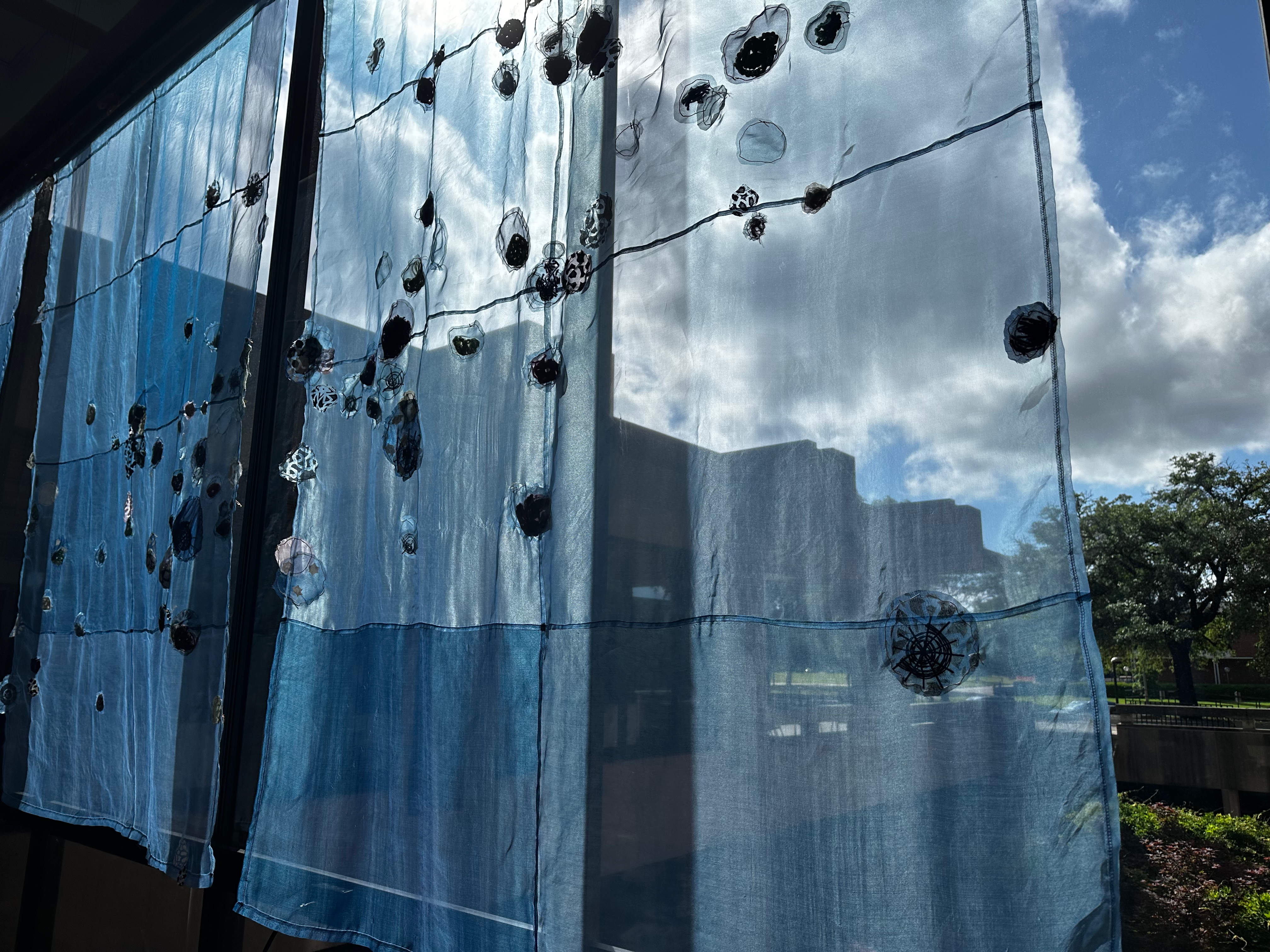 indigo dyed panels with fiber motifs as scatterplot points illuminated with light from windows immediately behind